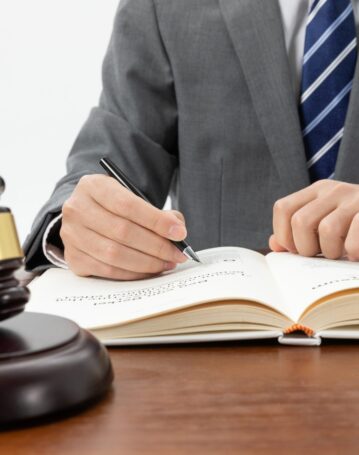 closeup-shot-person-writing-book-with-gavel-table