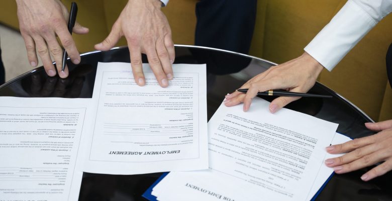 high-angle-hands-signing-documents